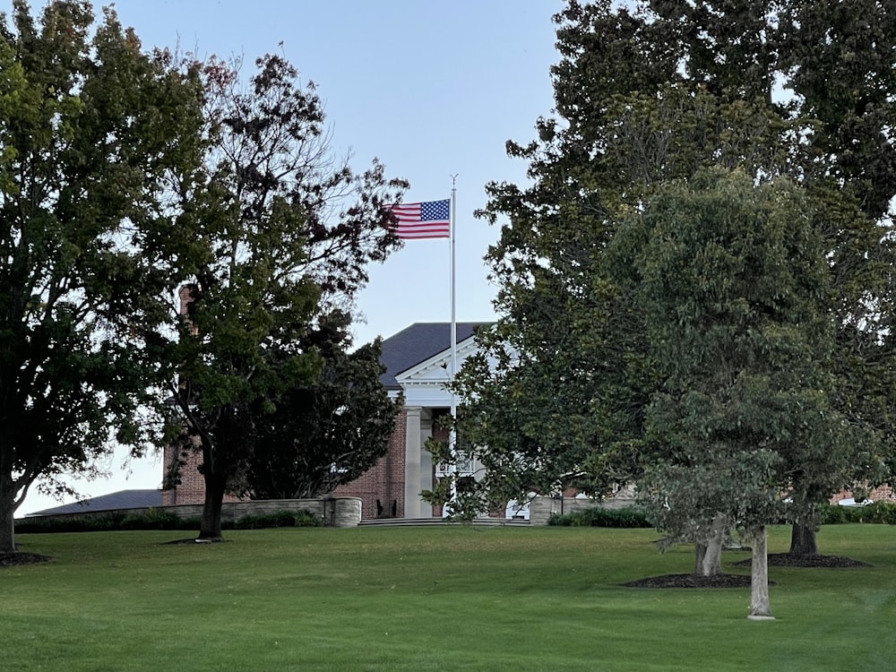 green grass field with green trees and us a flag on top during daytime