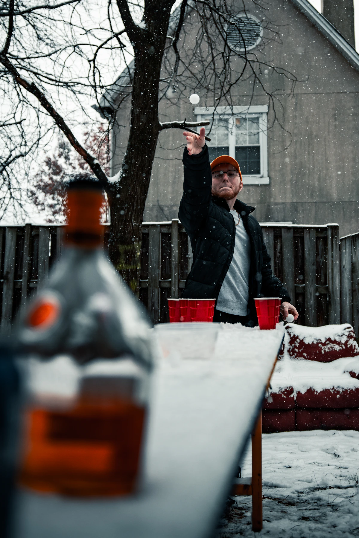 man in black jacket holding red and white ceramic mug