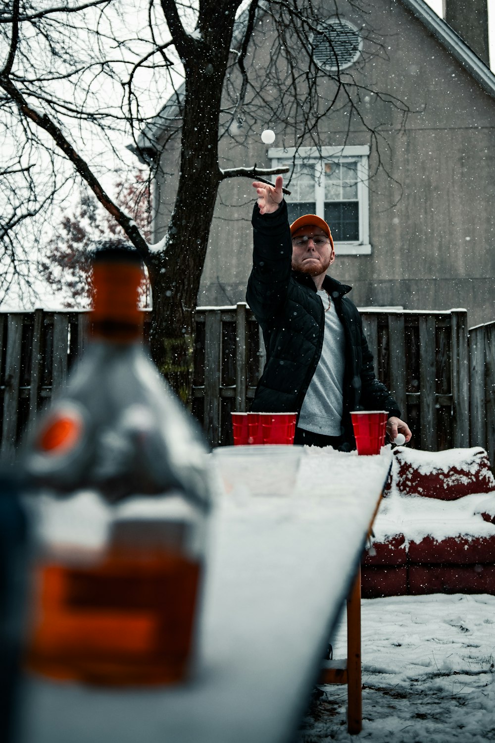 man in black jacket holding red and white ceramic mug