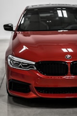 Close-up of a sleek sedan's front grille and headlights glistening under natural light.