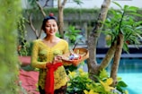 woman in yellow floral dress holding clear glass bowl with fruits