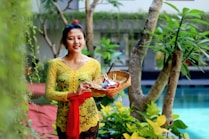 woman in yellow floral dress holding clear glass bowl with fruits