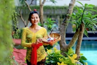 woman in yellow floral dress holding clear glass bowl with fruits