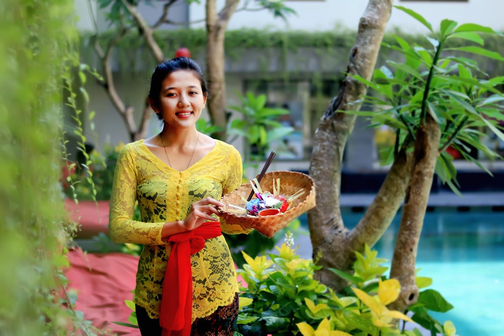 Frau in gelbem Blumenkleid mit klarer Glasschale mit Früchten