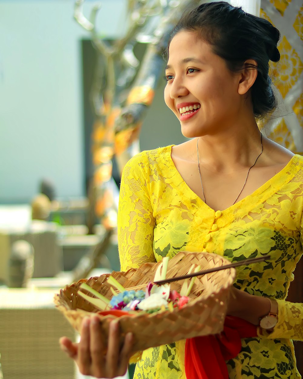 Mujer en vestido floral amarillo sosteniendo canasta de frutas