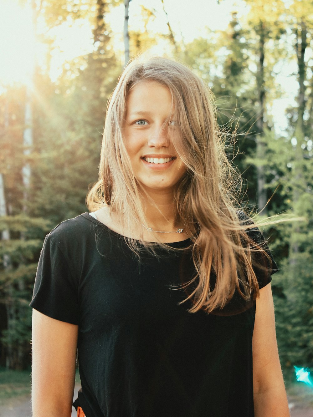 woman in black crew neck t-shirt standing near green trees during daytime