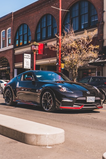 A sleek black sports car with red accents parked under city lights, showcasing aggressive street style and performance.