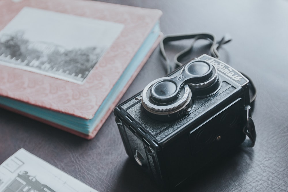 black and silver camera on white and red book