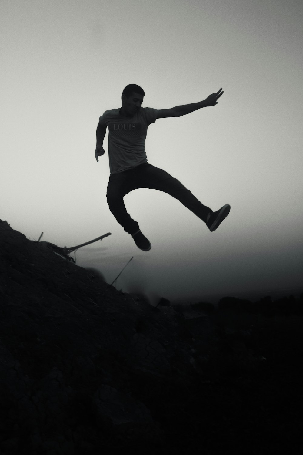 silhouette of man jumping on rocky hill during daytime