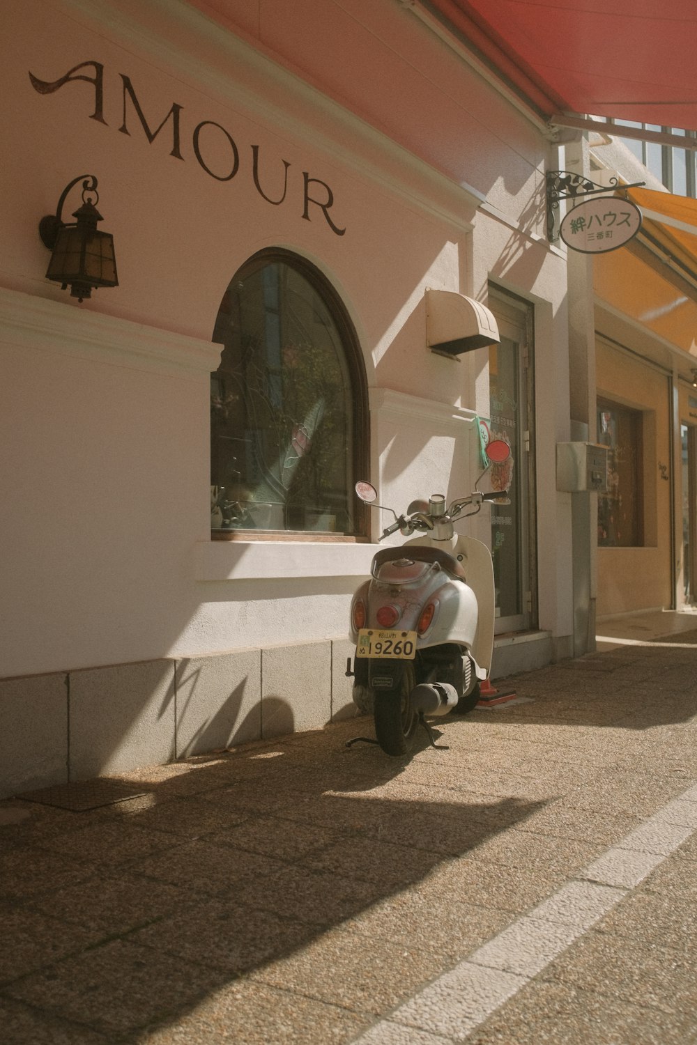 white and red motor scooter parked beside white concrete building during daytime