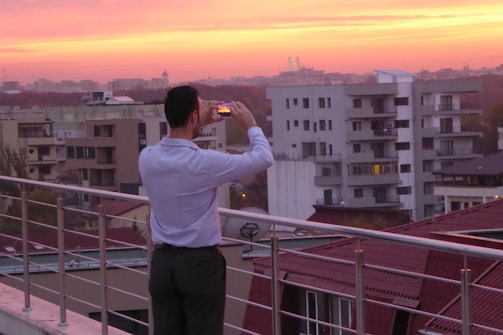 A vibrant travel influencer capturing a sunset on a rooftop in London.