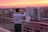 A vibrant travel influencer taking photos at a scenic hotel rooftop at sunset.