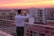 A vibrant travel influencer taking photos at a scenic hotel rooftop at sunset.