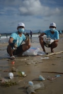 Volunteers cleaning a beach full of plastic waste on a sunny day.