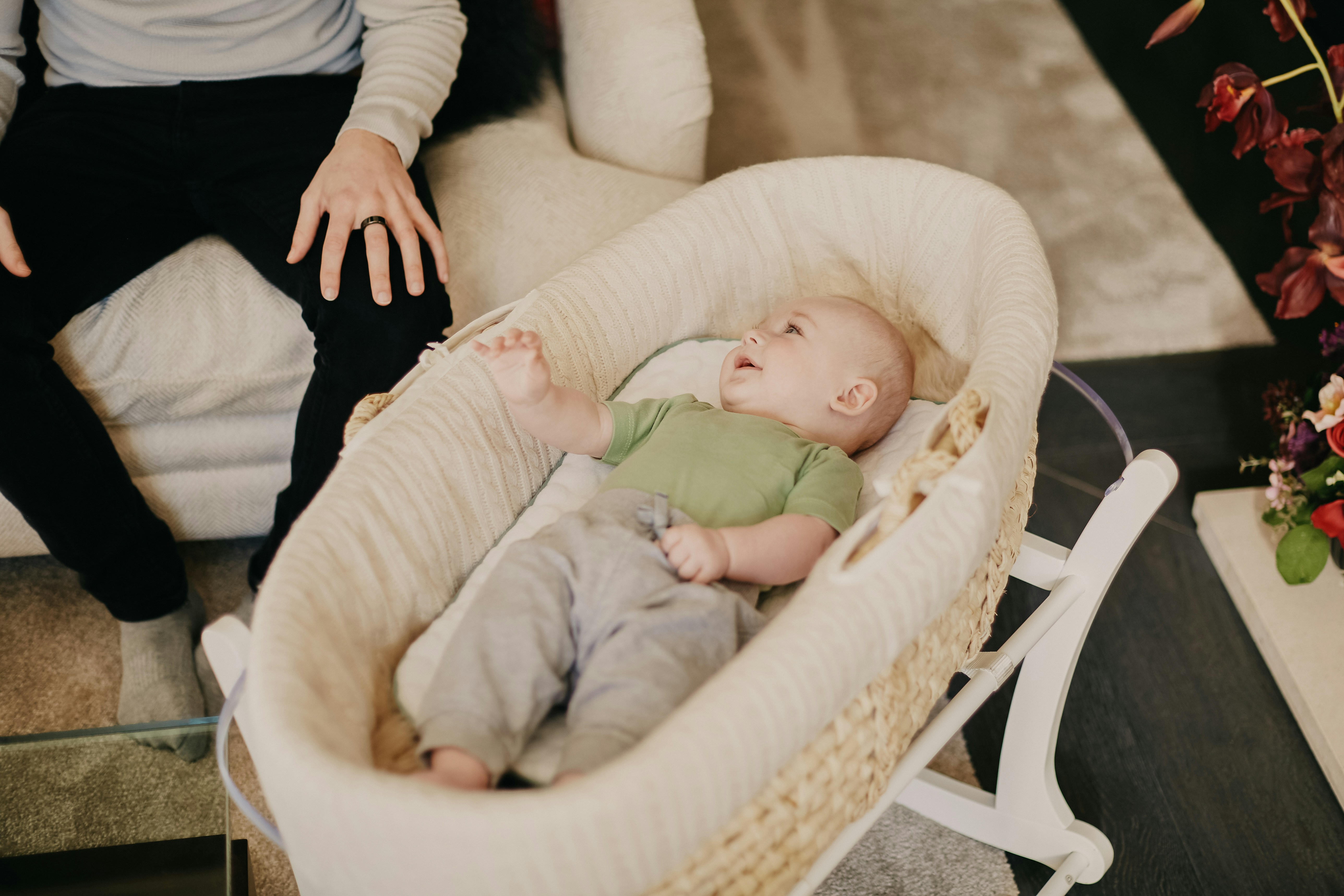 baby in green onesie lying on white and brown crib
