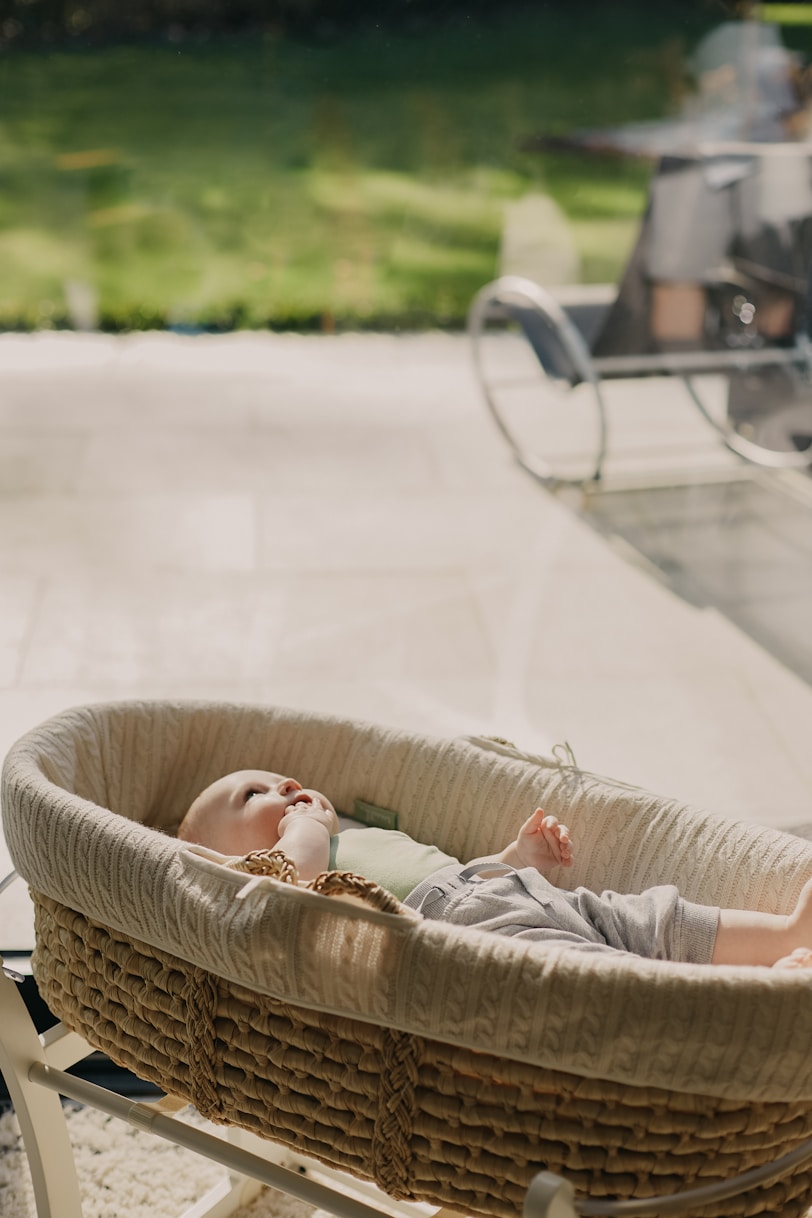 baby in white shirt lying on brown wicker basket