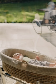 baby in white shirt lying on brown wicker basket
