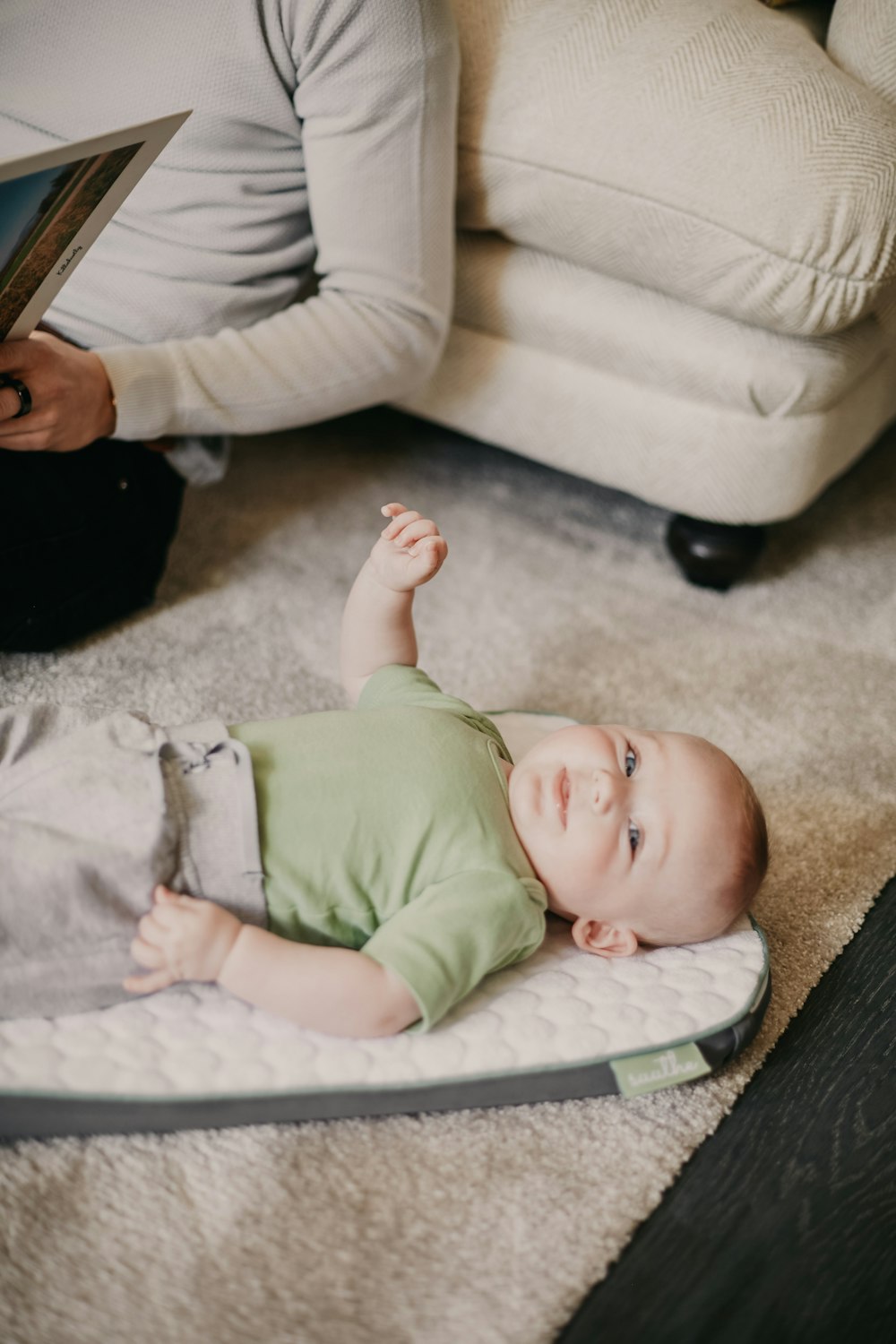 baby in green onesie lying on white textile