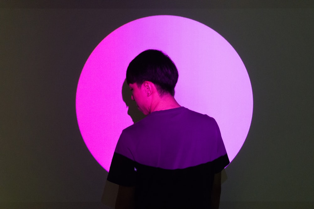 woman in purple shirt standing in front of pink wall