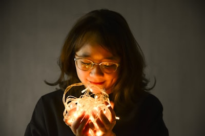 woman in black framed eyeglasses holding lighted candle cheerful zoom background