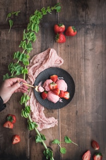 An overhead shot of a rustic wooden table scattered with fresh fruits and a bowl of babe ice cream melting slowly.