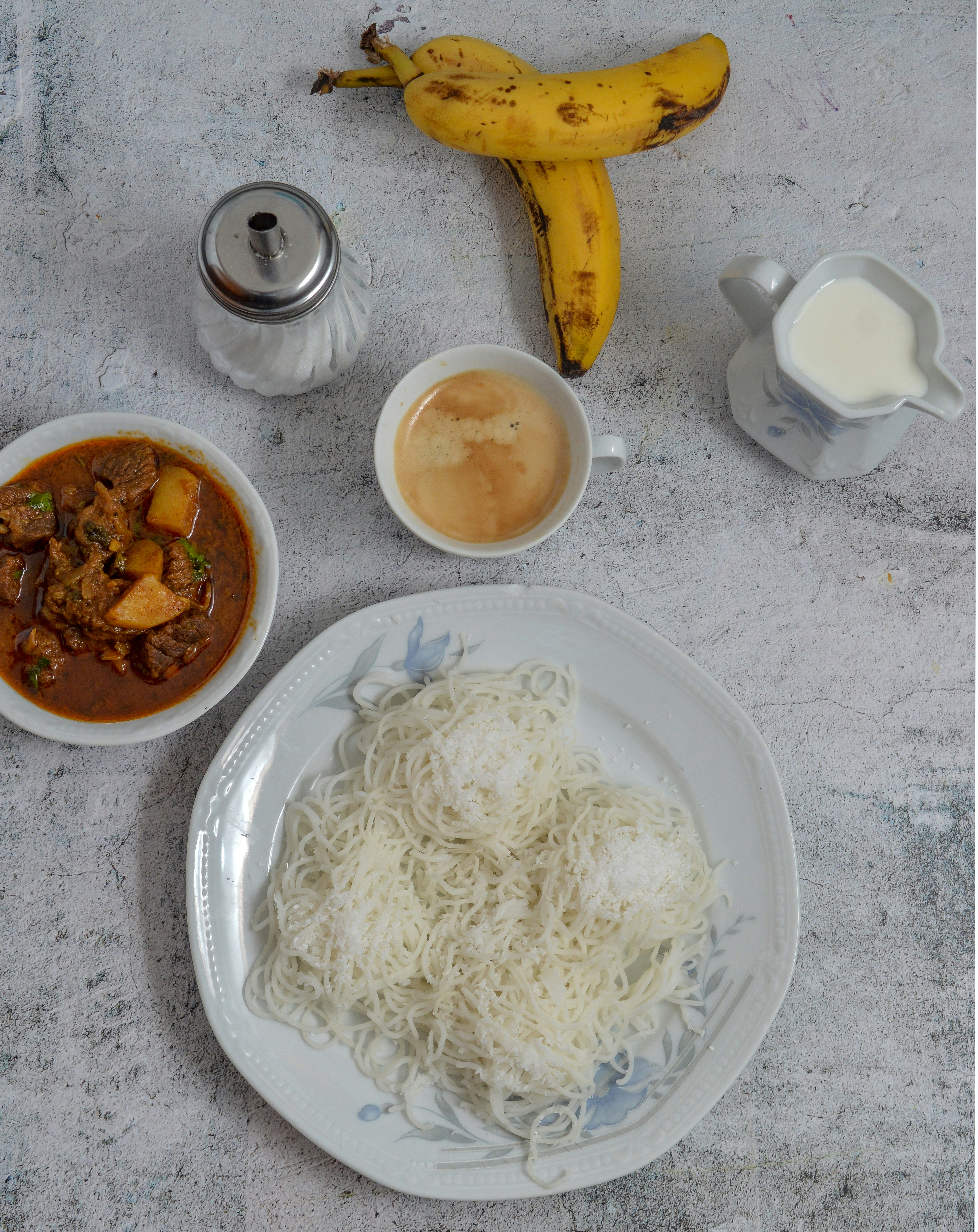 white ceramic plate with pasta and brown sauce