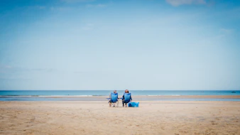 2 person sitting on beach sand during daytime