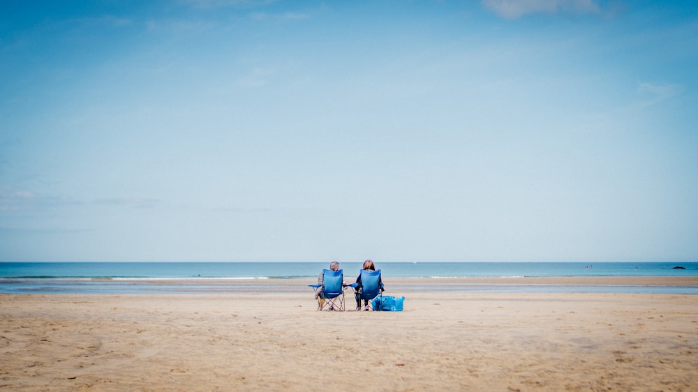 2 Personen sitzen tagsüber auf Strandsand