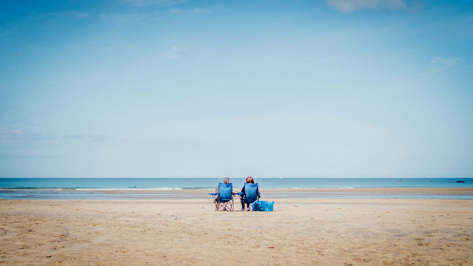 2 person sitting on beach sand during daytime