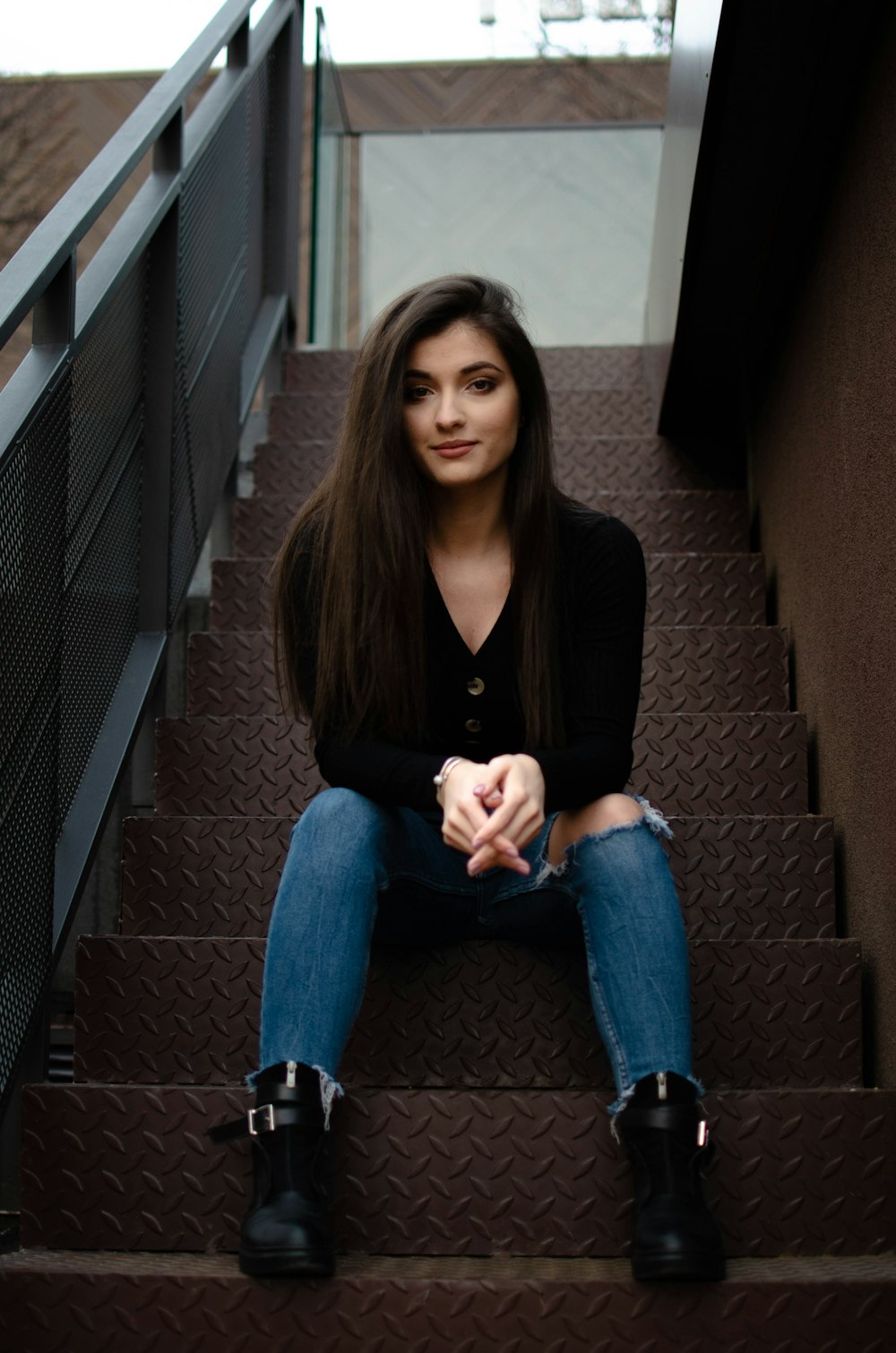 woman in black blazer and blue denim jeans sitting on stairs