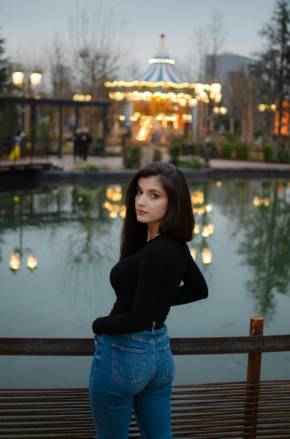 woman in black long sleeve shirt and blue denim shorts standing near body of water during