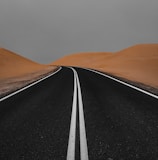 black asphalt road in the middle of desert