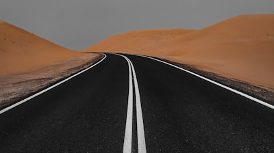 black asphalt road in the middle of desert