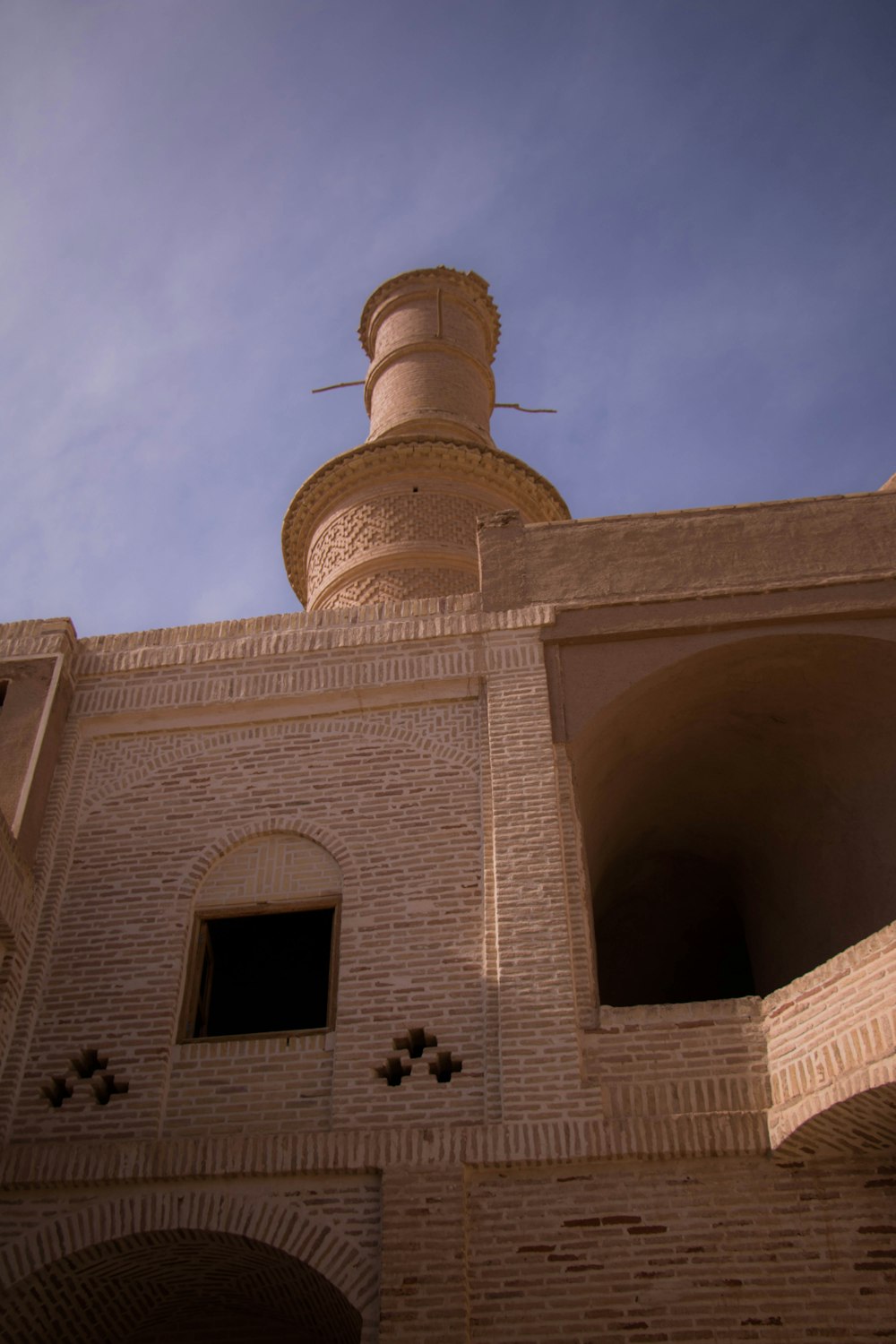 low angle photography of beige concrete building under blue sky during daytime