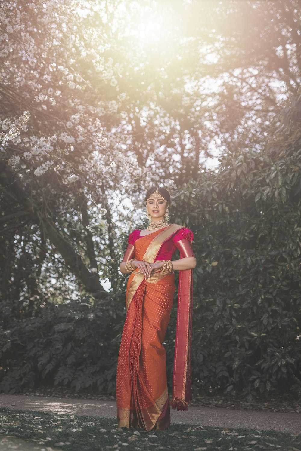 woman in red and brown sari standing under brown tree during daytime