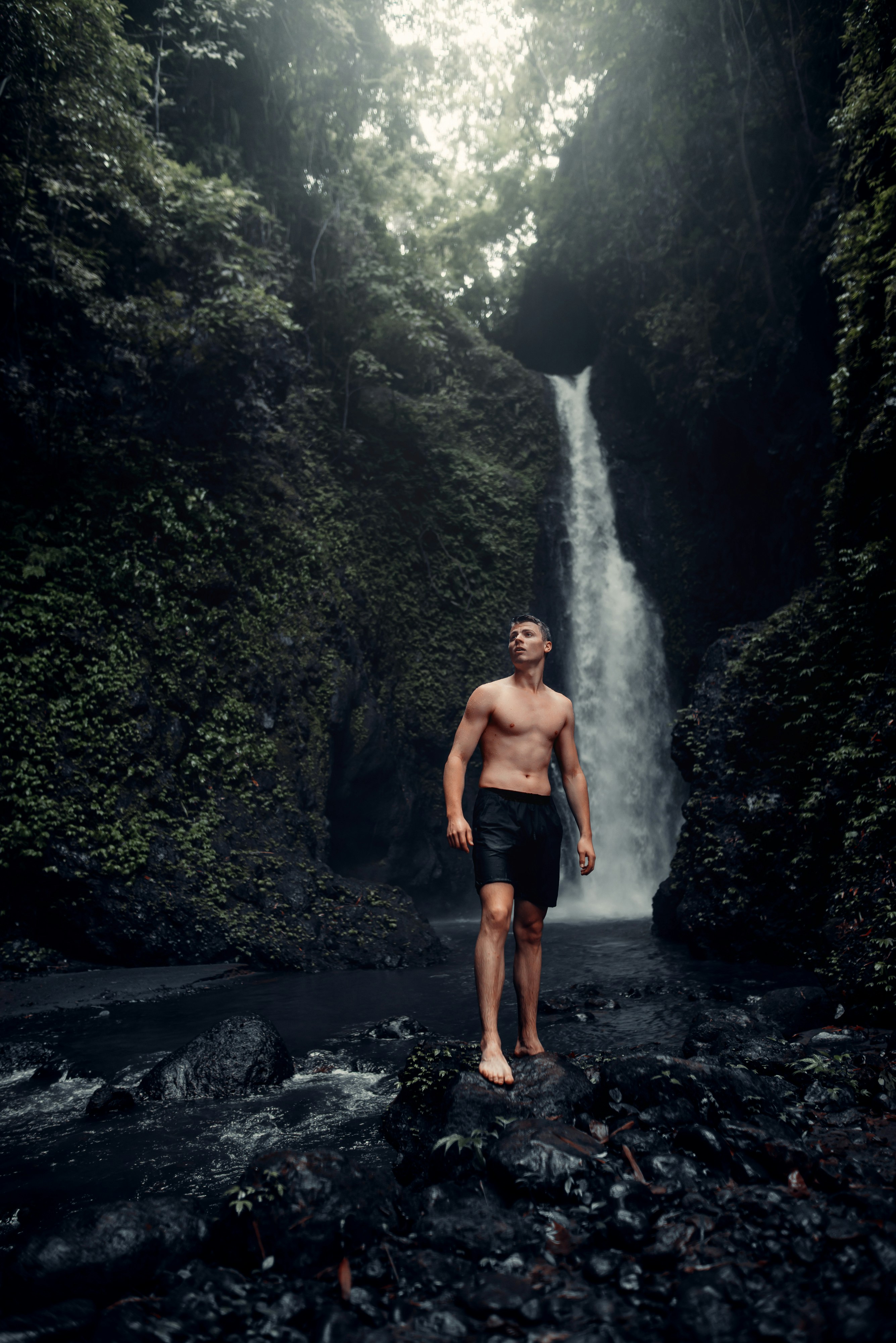 Pria bercelana pendek hitam berdiri di Rocky River di siang hari