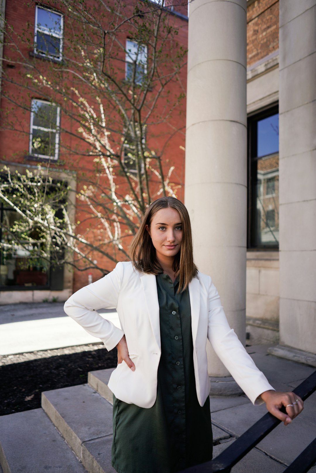 woman in white coat standing near brown bare tree during daytime