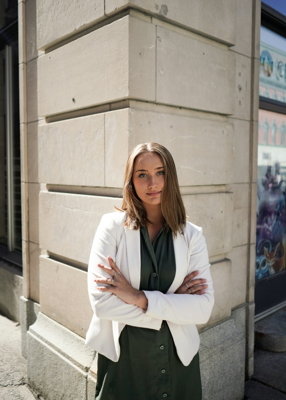 woman in white blazer standing beside beige concrete wall