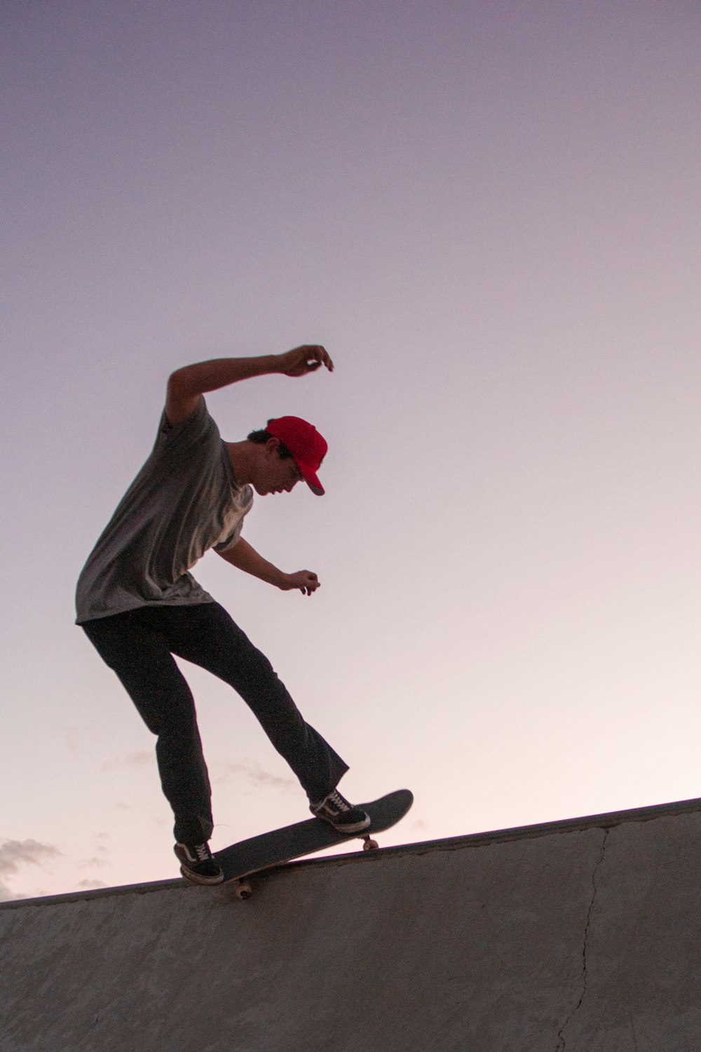 man in gray shirt and black pants doing stunts on gray concrete wall during daytime