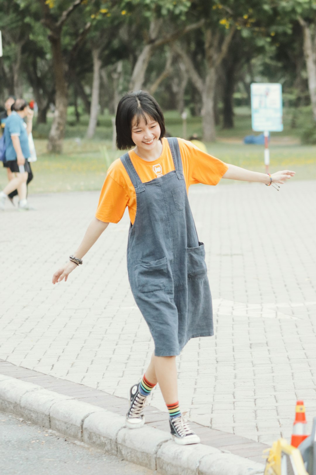 girl in yellow t-shirt and blue denim dungaree standing on gray concrete floor during daytime