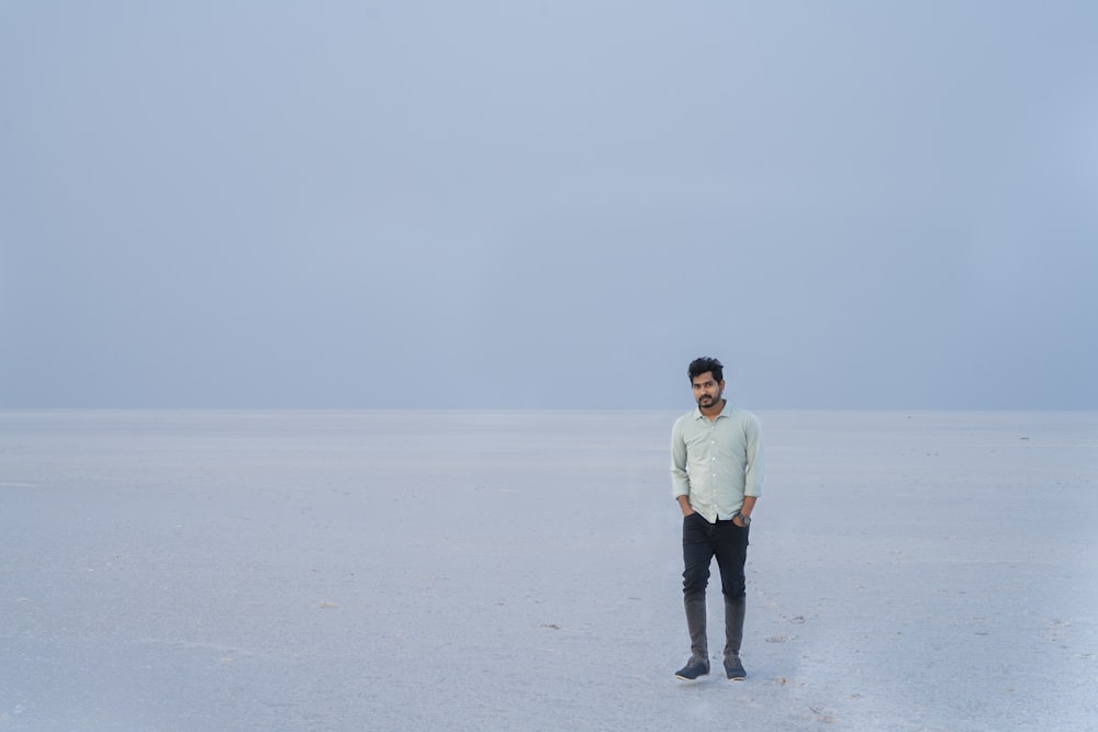 man in white dress shirt and black pants standing on white snow field during daytime