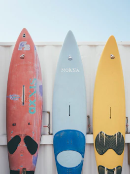 red and blue kayaks on white wooden fence