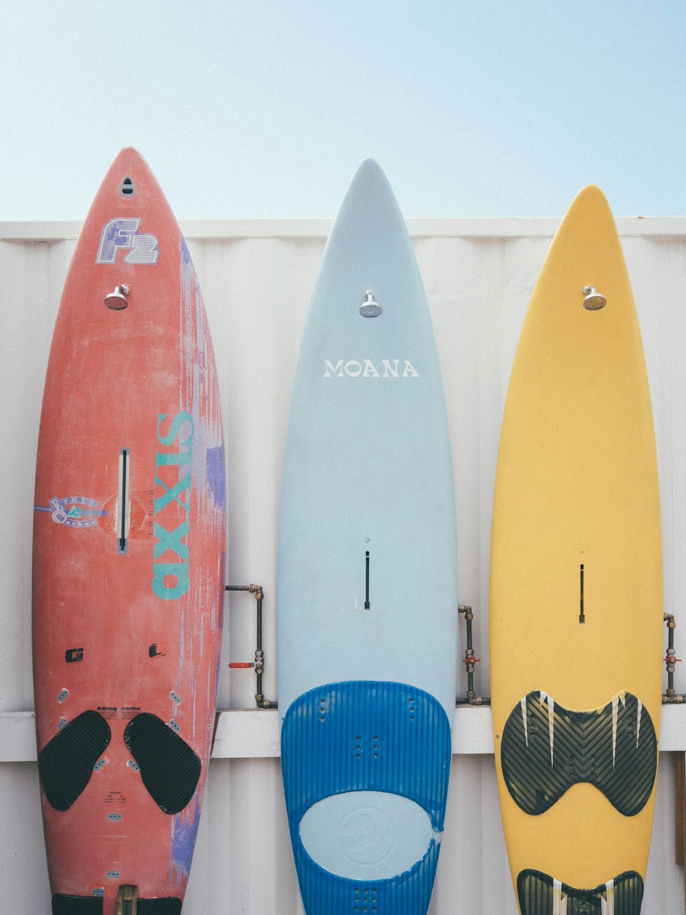 red and blue kayaks on white wooden fence