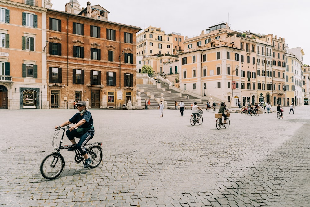 pessoas andando de bicicleta na estrada perto de um edifício de concreto marrom durante o dia