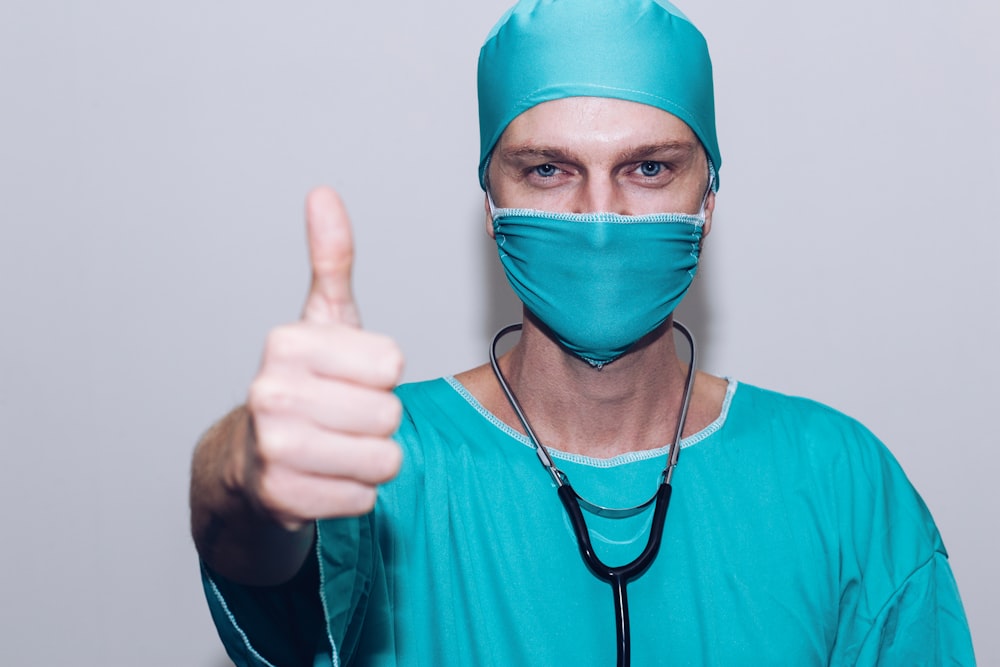 persona in camicia a maniche lunghe girocollo verde che indossa una maschera facciale blu