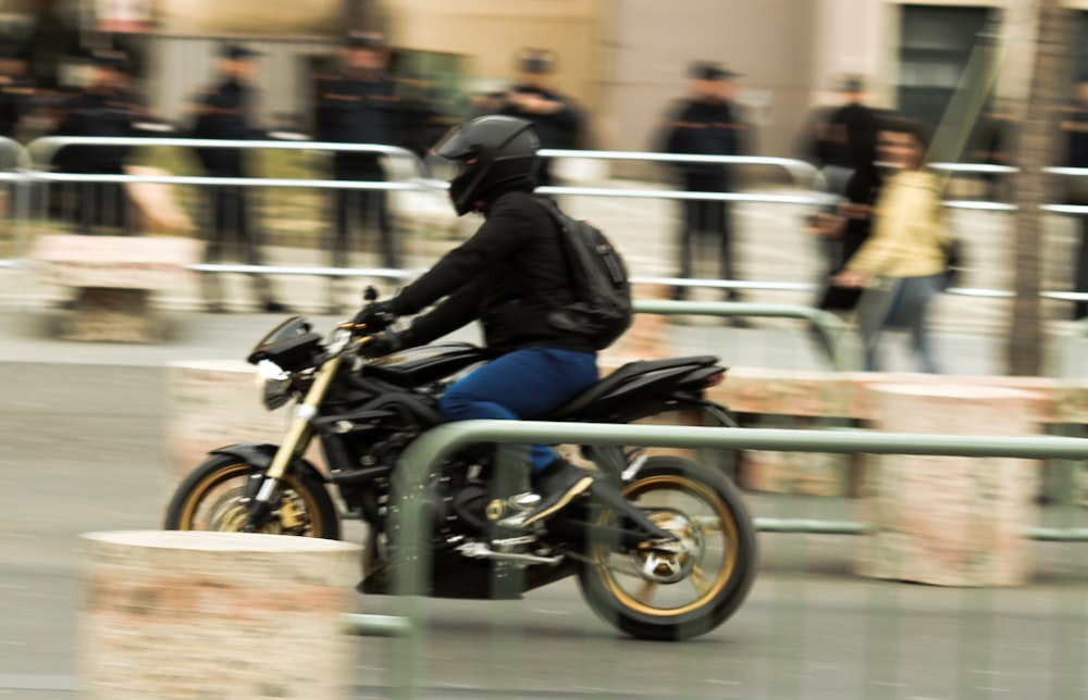 man in black jacket and blue denim jeans riding black motorcycle