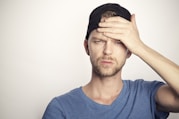 man in blue crew neck shirt covering his face