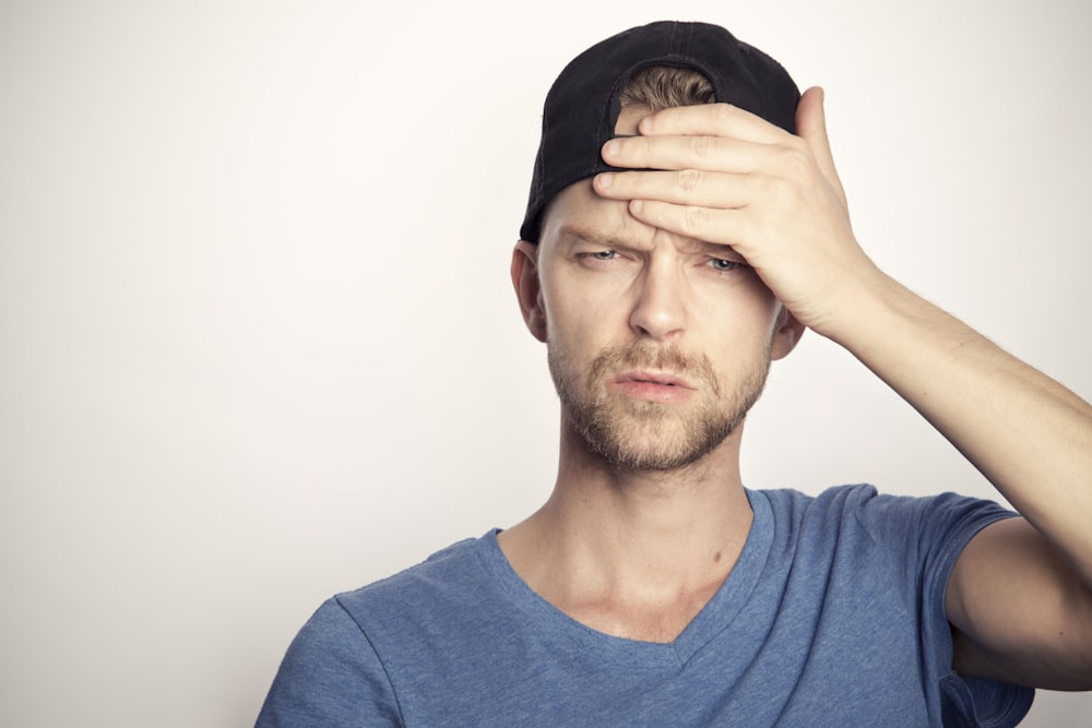 uomo in camicia girocollo blu che gli copre il viso