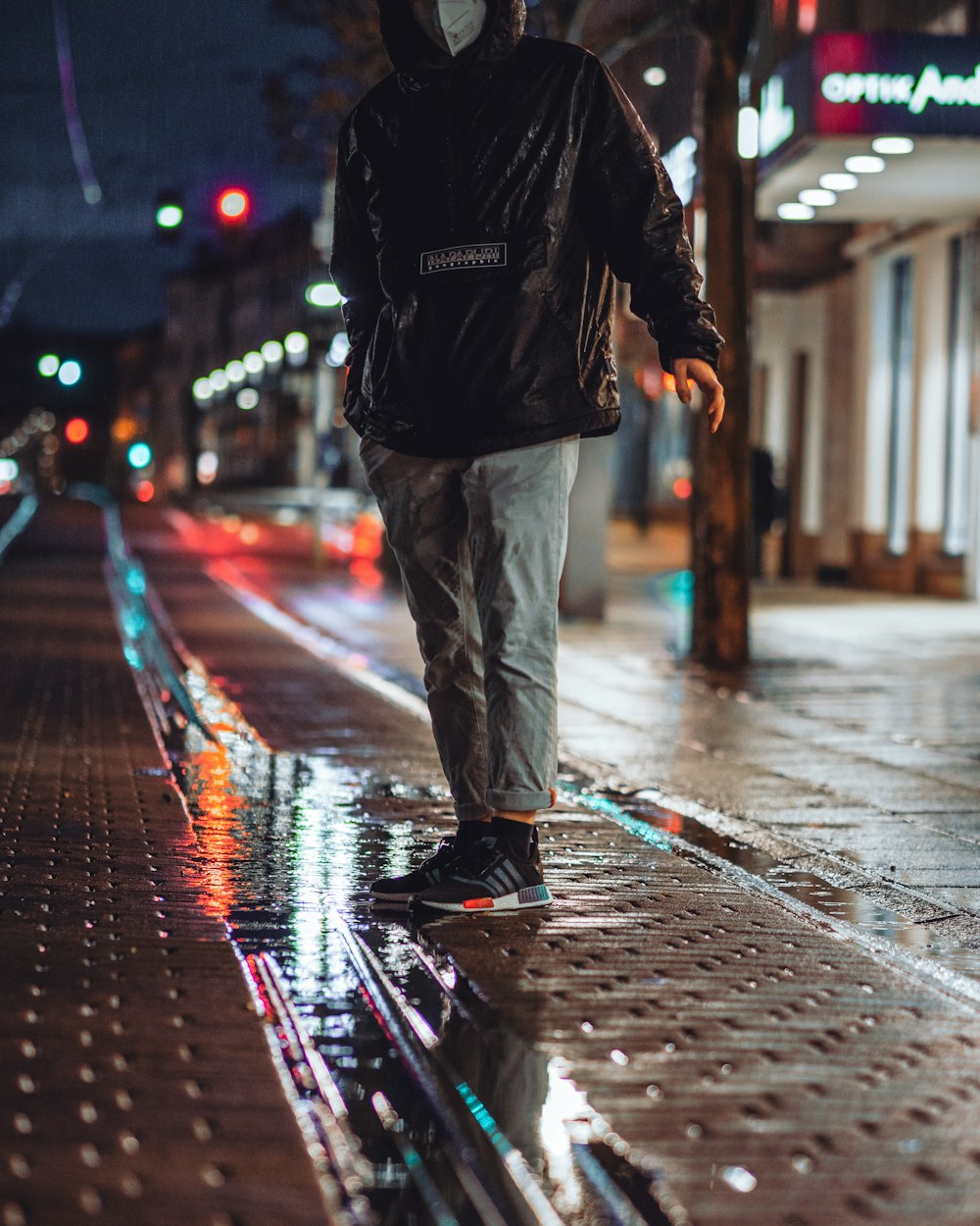 man in black jacket and gray pants walking on street during night time