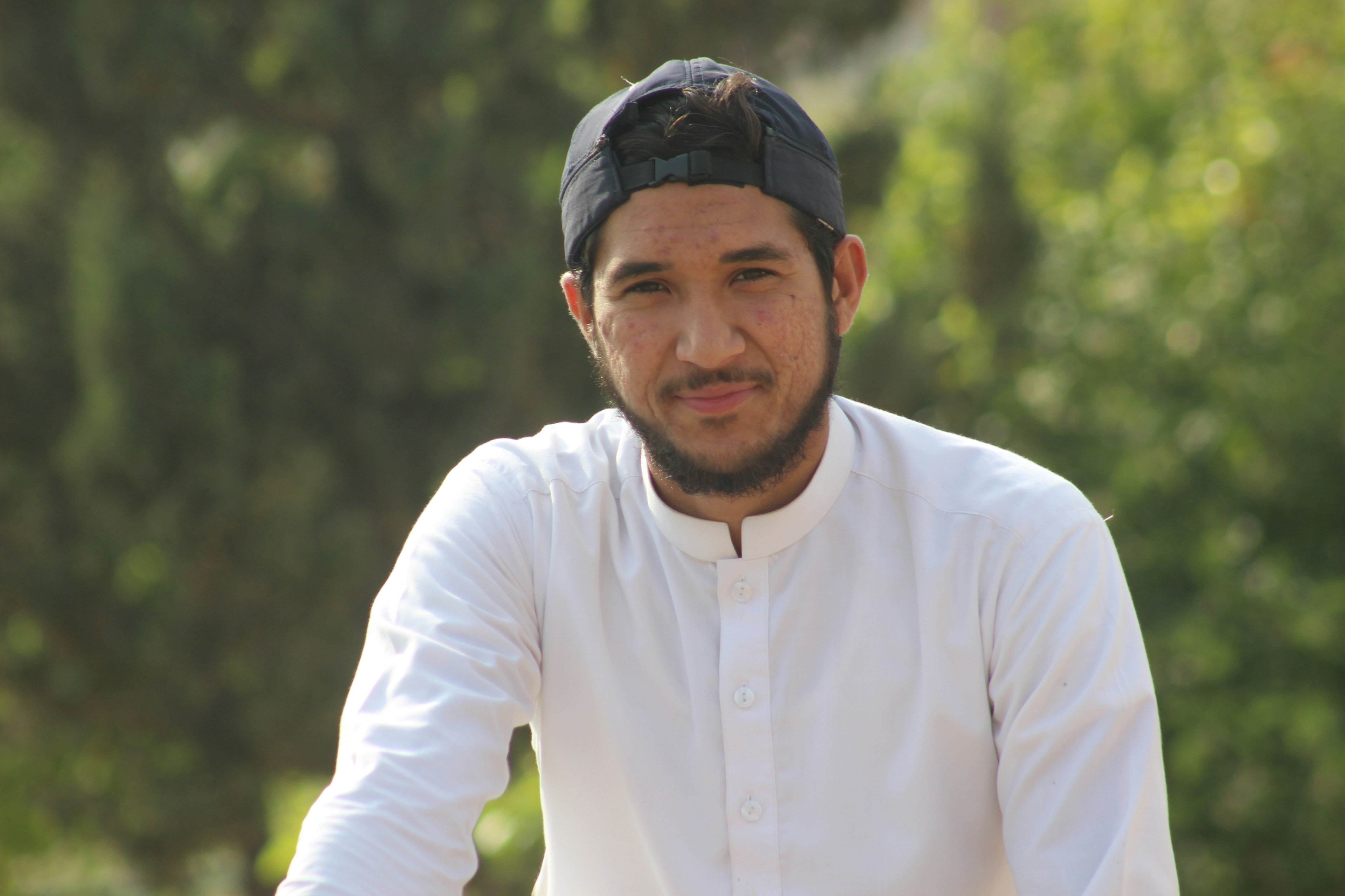 man in white dress shirt and black cap